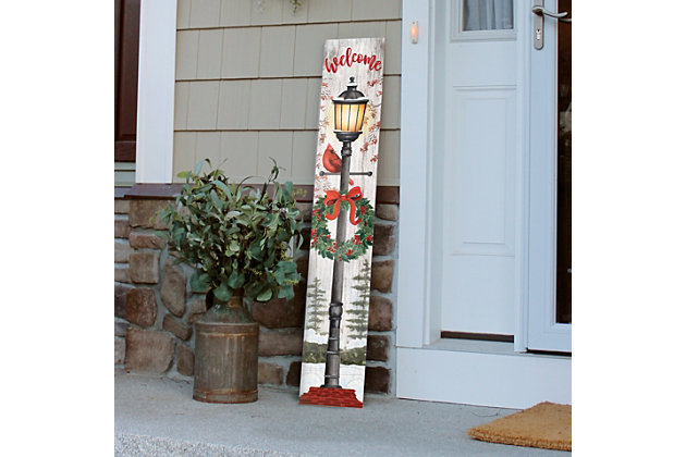 Spruce up your front porch with this rustic farmhouse welcome sign as you ring in the holidays. A beautiful lamppost adorns the indoor/outdoor Porch Board™, complete with a classic Christmas wreath and cardinal. This unique door sign is sure to turn heads while adding style and decor to your surroundings.Made of engineered wood | Weatherproof | Suitable for indoor/outdoor use | No assembly required | Made in the USA