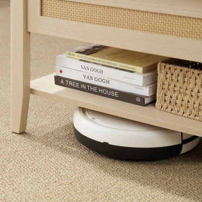 Close-up of lower shelf with books and a robotic vacuum under the table