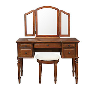 With all the allure of a treasured heirloom—at a fraction of the price—this beguiling 3-piece vanity set will fit right in. A softly padded seat welcomes, while the warm cherry-tone finish and tri-fold mirror are clear reflections of your good taste. And when you’ve perfected your look, five drawers keep the top uncluttered and essentials close at hand.Includes vanity, mirror and stool | Made of rubberwood and engineered wood | Cherry-tone finish | Stool with foam cushioned seat with cotton/polyester upholstery and turned spindle legs | Hinged tri-fold mirror | 5 drawers with raised frame fronts and antiqued brass-tone pulls | Assembly required | Ships in 2 boxes
