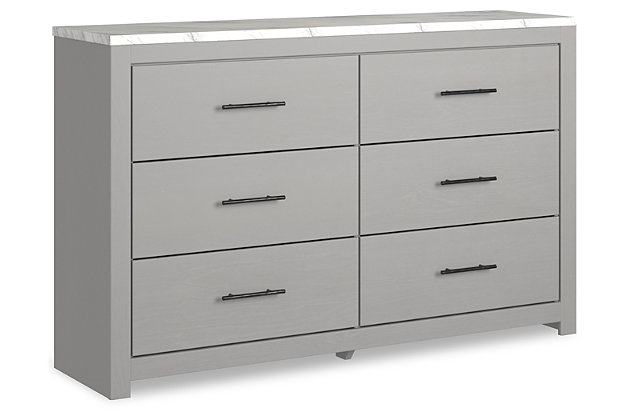 Cool, clean and casually modern. The Cottonburg dresser’s wispy dove gray finish and faux Calcutta marble top set the tone for your calming sanctuary. Large linear pulls add dimension and authenticity. Six smooth-gliding drawers neatly accommodate your wardrobe needs.Dresser only | Made of engineered wood (MDF/particleboard) | and decorative laminate | Wispy dove gray finish with replicated wood grain | Replicated Calcutta marble top | 6 smooth-gliding drawers with faux linen lining | Large scale dark colored handles | Safety is a top priority, clothing storage units are designed to meet the most current standard for stability, ASTM F 2057 (ASTM International) | Drawers extend out to accommodate maximum access to drawer interior while maintaining safety | Assembly required