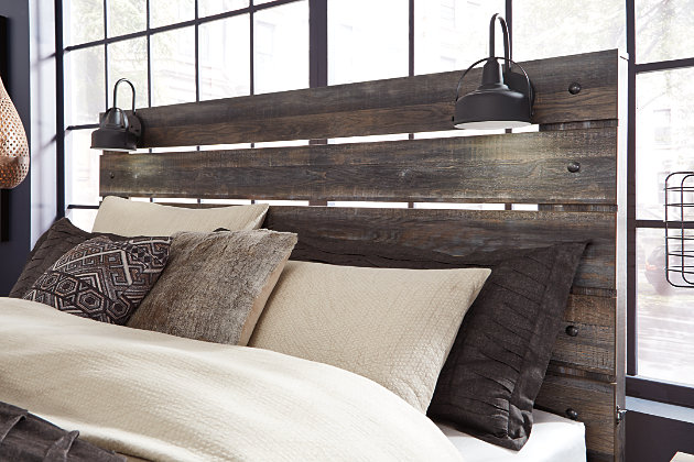 When merged in just the right way, rustic and industrial styles can make one happy marriage. Case in point: the Drystan queen panel headboard. A refined take on barn board beauty, its complex, replicated wood grain showcases hints of burnt orange and teal tones for a sense of weatherworn authenticity. Love to read in bed? You’re sure to find the pair of retro-chic light sconces and USB plug-ins on the open-slat style headboard such a bright idea.Headboard only | Hardware not included | Made of engineered wood and decorative laminate | Brown rustic finish with burnt orange and teal accents in a replicated wood grain with authentic touch | 2 decorative sconce lights, LED with 3 AA batteries | Dual USB charger | Power cord included; UL Listed | ¼" bolts are needed to attach headboard to existing bed frame | Bolt length depends on thickness of your bed frame | Assembly required