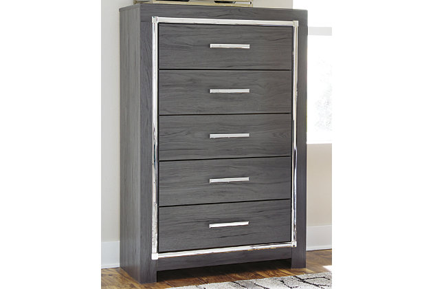 Reminiscent of Hollywood glamour of yesteryear, the Lodanna chest of drawers interprets luxury in a decidedly modern way. Dazzling gray finish and faceted chrome-tone accents enhance the star power, while five smooth-gliding drawers provide enough storage to appease your inner diva.Made of engineered wood (MDF/particleboard) and decorative laminate | Gray finish with replicated wood grain | Faceted chrome-tone pulls and accents | 5 smooth-operating drawers | Drawer interiors are lined with a faux linen laminate for a clean, finished look | Safety is a top priority, clothing storage units are designed to meet the most current standard for stability, ASTM F 2057 (ASTM International) | Drawers extend out to accommodate maximum access to drawer interior while maintaining safety
