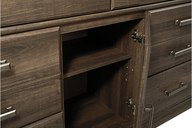 Get the look of posh barn wood without setting foot in a salvage yard. Replicated rough-sawn oak of the Juararo dresser and mirror set has a vintage finish that is reminiscent of a timeworn family heirloom. Warm, rustic and naturally beautiful, it’s just got that ageless appeal. Sleek, mod pulls in a pewter tone are a snappy finishing touch.Made of engineered wood and decorative laminate | Vintage aged brown rough sawn finish over replicated oak grain | Pewter-tone hardware | 6 drawers | 1 cabinet with 1 adjustable shelf | Mirror attaches to back of dresser | Safety is a top priority, clothing storage units are designed to meet the most current standard for stability, ASTM F 2057 (ASTM International) | Drawers extend out to accommodate maximum access to drawer interior while maintaining safety | Assembly required | Estimated Assembly Time: 5 Minutes