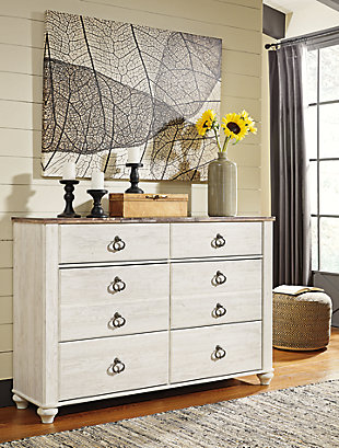 The Willowton dresser is the ultimate statement piece for your coastal cottage or shabby chic inspired retreat. Whitewashed finish on the drawers and sides is wonderfully easy on the eyes. Paired with the unique plank-effect top, it’s a driftwoody look that has our minds drifting away to beachy-keen escapes.Dresser only | Made of engineered wood (MDF/particleboard) and decorative laminate | Whitewash replicated worn through paint with authentic touch | Replicated wood grained block pattern with authentic touch | Antiqued brass-tone ring-pull hardware | 6 smooth-gliding drawers | Safety is a top priority, clothing storage units are designed to meet the most current standard for stability, ASTM F 2057 (ASTM International) | Drawers extend out to accommodate maximum access to drawer interior while maintaining safety | Assembly required