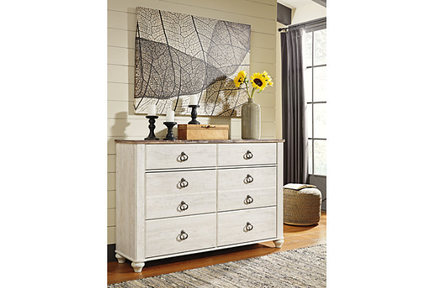 The Willowton dresser is the ultimate statement piece for your coastal cottage or shabby chic inspired retreat. Whitewashed finish on the drawers and sides is wonderfully easy on the eyes. Paired with the unique plank-effect top, it’s a driftwoody look that has our minds drifting away to beachy-keen escapes.Dresser only | Made of engineered wood (MDF/particleboard) and decorative laminate | Whitewash replicated worn through paint with authentic touch | Replicated wood grained block pattern with authentic touch | Antiqued brass-tone ring-pull hardware | 6 smooth-gliding drawers | Safety is a top priority, clothing storage units are designed to meet the most current standard for stability, ASTM F 2057 (ASTM International) | Drawers extend out to accommodate maximum access to drawer interior while maintaining safety | Assembly required