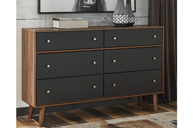With its ultra clean-lined profile, minimalist-chic appeal and distinctive splayed legs, the Daneston dresser has all the signature elements of high-end Scandinavian style: with a twist. A tantalizing two-tone finish blends replicated walnut grain with a matte black on the flush-mount drawer fronts. Six deep, smooth-gliding drawers are generously accommodating.Dresser only | Made of engineered wood (MDF/particleboard) | Two-tone finish (replicated walnut grain and matte gray) | Burnished goldtone hardware | 6 smooth-gliding drawers with faux linen lining | Safety is a top priority, clothing storage units are designed to meet the most current standard for stability, ASTM F 2057 (ASTM International) | Drawers extend out to accommodate maximum access to drawer interior while maintaining safety