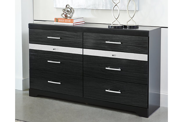 Starry, starry nights. Inspired by Hollywood glam, the richly styled Starberry dresser steals the show in a simply stunning way. The dresser’s replicated walnut grain is enriched with a high-gloss black finish, made even more dramatic with chrome handles with faux crystals. Two felt-bottom six-compartment jewelry drawers with silver glitter finish fronts accentuate a clean-lined, contemporary aesthetic.Dresser only | Made of engineered wood (MDF/particleboard) and decorative laminate | High gloss black finish with replicated straight silver walnut grain framed in black finish | Silvertone glitter accent | 6 smooth-gliding drawers plus 2 felt-lined 6-compartment jewelry drawers | Chrome-tone hardware with faux crystals | Safety is a top priority, clothing storage units are designed to meet the most current standard for stability, ASTM F 2057 (ASTM International) | Drawers extend out to accommodate maximum access to drawer interior while maintaining safety | Assembly required