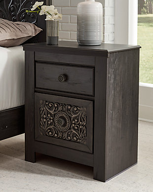 Showcase your trend-setting spirit with the Paxberry nightstand. Inspired by bohemian tapestries, exquisite carved medallion pattern is a testament to boho-chic style. Sophisticated dark finish sets a foundation for a room bursting with personality. Best of all, nightstand includes handy USB charging ports.Made of engineered wood (MDF/particleboard) and decorative laminate | Vintage aged black/brown finish over replicated oak grain | Hardware features a worn-through painted effect | 2 smooth-gliding drawers with faux linen lining | USB chargers | Power cord included; UL Listed | Assembly required