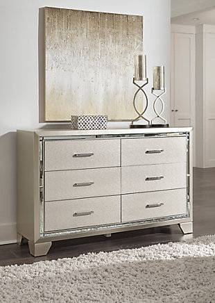 Taking its cues from Hollywood Regency interiors, the Lonnix dresser is puttin’ on the ritz in a big way. The dresser’s ultra-clean profile is elevated with a spectacular metallic silvertone finish made all the more interesting with a hint of embossed texturing on the sleek, flush-mount drawers. The beveled mirror trimwork that frames the dresser creates a rich, reflective effect, while ultra-modern nickel-tone pulls with faux crystal insets serve as a fabulous finishing touch.Dresser only | Made of wood and engineered wood | Silvertone metallic finish | 6 smooth-gliding drawers with dovetail construction | Beveled mirror trim | Embossed, textural drawer fronts | Bright nickel-tone pulls with faux crystal insets | Includes tipover restraint device | Estimated Assembly Time: 30 Minutes