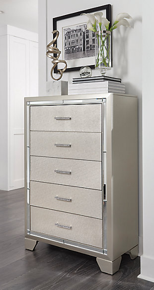 Taking its cues from Hollywood Regency interiors, the Lonnix chest of drawers is puttin’ on the ritz in a big way. The chest’s ultra-clean profile is elevated with a spectacular metallic silvertone finish made all the more interesting with a hint of embossed texturing on the sleek, flush-mount drawers. The beveled mirror trimwork that frames the chest creates a rich, reflective effect, while ultra-modern nickel-tone pulls with faux crystal insets serve as a fabulous finishing touch.Made of wood and engineered wood | Silvertone metallic finish | 5 smooth-gliding drawers with dovetail construction | Beveled mirror trim | Embossed, textural drawer fronts | Bright nickel-tone pulls with faux crystal insets | Estimated Assembly Time: 30 Minutes