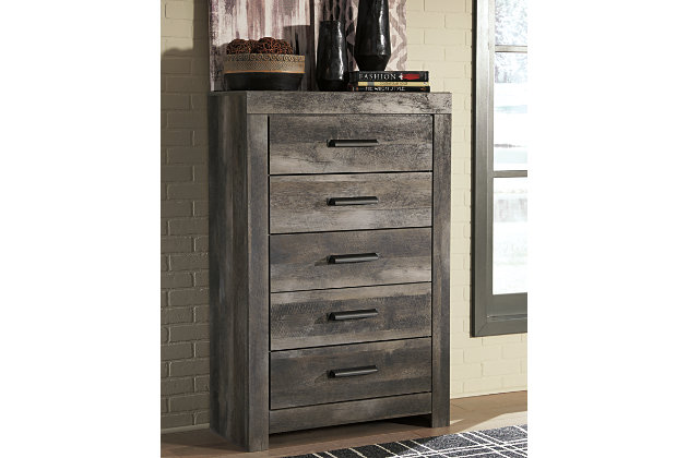 The Wynnlow chest of drawers is sure to win your heart with its daring designer take on modern rustic. The bedroom chest’s crisp, clean and minimalist-chic profile is enriched with a striking replicated oak grain with thick plank styling and a weathered gray finish for that much more authentic character. Large-scale hooded pulls gracing the flush-mount drawers add such a distinctive twist.Made of engineered wood (MDF/particleboard) and decorative laminate | Rustic gray planked replicated oak grain with authentic touch | Hooded pull hardware in dark finish | 5 smooth-gliding drawers | Safety is a top priority, clothing storage units are designed to meet the most current standard for stability, ASTM F 2057 (ASTM International) | Drawers extend out to accommodate maximum access to drawer interior while maintaining safety | Assembly required