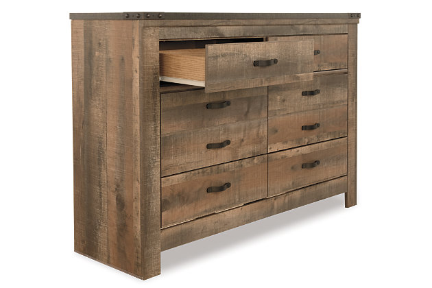 Whether she loves horses or he's a cowboy at heart, the Trinell dresser matches their authenticity. Rustic finish, plank-style details and nailhead trim pay homage to reclaimed barn wood, making for a chic look loaded with charm. Six roomy drawers keep clothing or toys nicely reined in.Dresser only | Made of engineered wood (MDF/particleboard) and decorative laminate | Warm rustic plank finish over replicated oak grain and authentic touch | Antiqued bronze-tone hardware | 6 smooth-operating drawers | Nailhead accents | Safety is a top priority, clothing storage units are designed to meet the most current standard for stability, ASTM F 2057 (ASTM International) | Drawers extend out to accommodate maximum access to drawer interior while maintaining safety | Assembly required