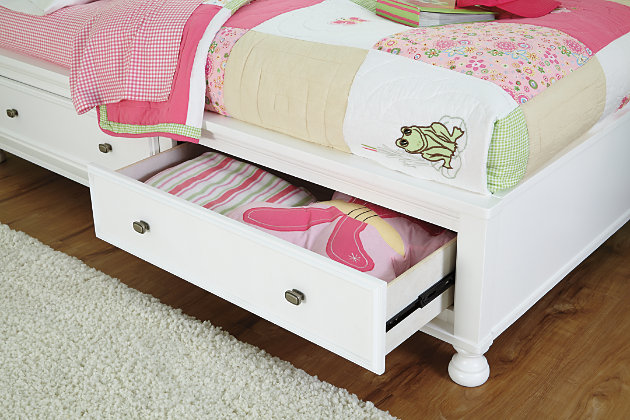 Let your country fresh style shine through with the bright and cheerful Kaslyn twin bookcase bed. The clean, crisp lines flow beautifully with cottage-quaint and shabby chic aesthetics. Headboard provides storage and display space for books and favorite odds and ends. Footboard's roomy drawers lend ample stowage to help them keep their room nice and tidy. Mattress available, sold separately.Made of veneers, wood and engineered wood | Aged nickel-tone hardware | Headboard with 7 storage cubbies and cutouts for wire management | Footboard with turned bun feet and 2 smooth-operating drawers with dovetail construction | Box spring not needed | Assembly required | Estimated Assembly Time: 115 Minutes