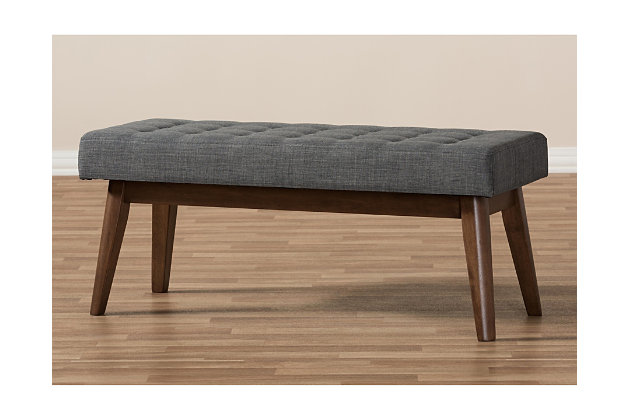What a striking choice for mid-century modern and fashion-forward spaces. Sumptuously cushioned upholstered bench in dark gray is sure to make a high-style addition to your home. Fabulous in an entryway or under a window, it’s equally at home at the foot of the bed.Made of wood | Light gray polyester upholstery | High-density foam cushioning | Button-tufted seat | Walnut-tone legs | Some assembly required