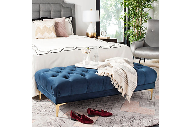 Create an instant oasis in your living room with this decadent tufted rectangular bench. Extravagant yet versatile, its sumptuous velvet upholstery is paired with a classic brass-tone finish on chic modern legs. Use it as a coffee table or extra seating with a truly contemporary touch.Made with iron | Upholstered in navy tufted velvet over cushioned seat | Brass-tone finish |  assembly required