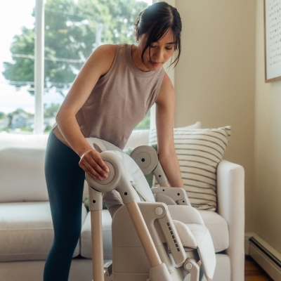Woman folding or adjusting high chair at home