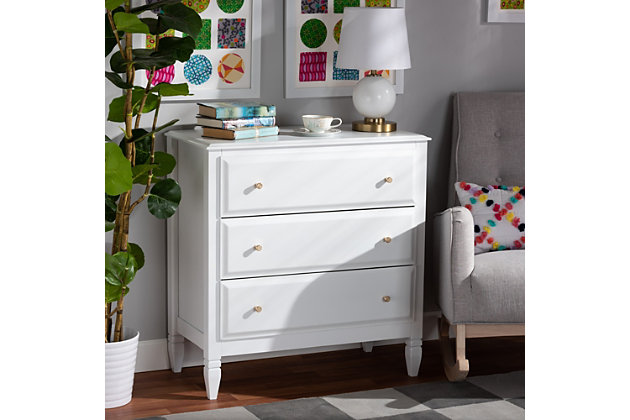 A classic silhouette receives a glamorous update in the Naomi chest. Made in Malaysia, this wooden chest displays a polished white finish that brightens any space. The tabletop is well suited for a lamp and trinkets, while three drawers provide ample storage space for clothing and linens. Each drawer is adorned with a striking gold-tone knob that adds a touch of glamour. Inspired by traditional design, the Naomi features tapered feet with recessed detailing. Requiring assembly, the Naomi chest strikes the optimal balance between classic and contemporary for a look that enhances any bedroom.  Classic and transitional chest | White finish | Three (3) drawers | Round gold-tone metal knobs | Tapered feet | Assembly required