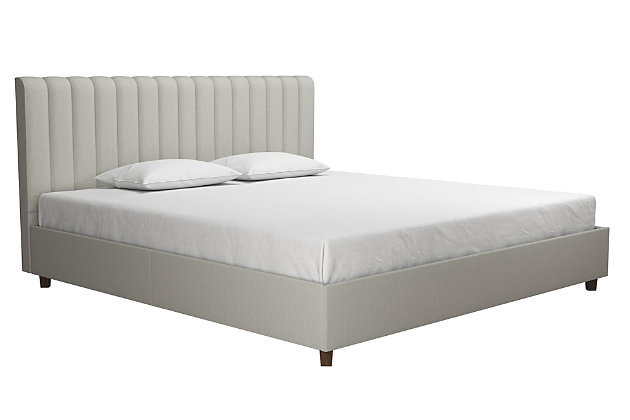 Luxury and glamour are in every detail of the Novogratz Brittany Upholstered Bed. Designed with a lavish modern style, this platform bed has a ribbed tufted headboard and oak colored legs that make it the perfect statement piece. The Brittany bed is made with a robust wood frame and upholstered in premium linen, adding elegance to your room. It comes with a bentwood slat system that provides optimal support as the slats adapt to the pressure exerted on them. It also includes side rails and additional metal legs to ensure stability and support. The comfortable cushioning of the headboard gives your body all the support needed to sit and relax. Just add the Novogratz Atlas Hybrid Mattress, a couple of pillows and a comfy duvet and you’ll be all set! Available in multiple colors and sizes.Designed with a lavish modern style in premium linen upholstery. Ribbed tufted headboard and oak colored legs | Robust wood frame construction that includes side rails and additional metal legs to ensure stability and support | Bentwood slat system provides optimal support as the slats adapt to the pressure exerted on them. No box spring required | Assembly Required
