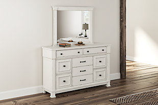 Given just enough distressing for family heirloom charm, the Jennily dresser is a mastery in modern farmhouse style. The ultimate choice for a dreamy bedroom retreat, its antiqued white finish is wonderfully easy on the eyes. Sturdy silhouette with bold pilasters gives this 9-drawer dresser such a rich, substantial presence. Various drawer sizes nicely accommodate, while combination of flush mount and framed drawer fronts is an inspired touch.Dresser only | Made of wood and engineered wood | Antiqued white finish | Rubbed dark metal hardware | 9 smooth-gliding drawers | Top 2 drawers felt lined | Includes tipover restraint device | Estimated Assembly Time: 15 Minutes