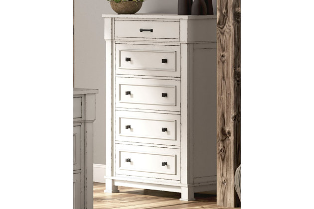 Given just enough distressing for family heirloom charm, the Jennily chest of drawers is a mastery in modern farmhouse style. The ultimate choice for a dreamy bedroom retreat, its antiqued white finish is wonderfully easy on the eyes. Sturdy silhouette with bold pilasters gives this bedroom chest such a substantial presence. Combination of flush mount and framed drawer fronts is an inspired touch.Made of wood and engineered wood | Antiqued white finish | Rubbed dark metal hardware | 5 smooth-gliding drawers | Top drawer felt lined | Includes tipover restraint device | Small Space Solution