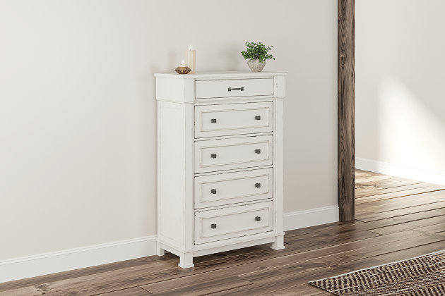 Given just enough distressing for family heirloom charm, the Jennily chest of drawers is a mastery in modern farmhouse style. The ultimate choice for a dreamy bedroom retreat, its antiqued white finish is wonderfully easy on the eyes. Sturdy silhouette with bold pilasters gives this bedroom chest such a substantial presence. Combination of flush mount and framed drawer fronts is an inspired touch.Made of wood and engineered wood | Antiqued white finish | Rubbed dark metal hardware | 5 smooth-gliding drawers | Top drawer felt lined | Includes tipover restraint device | Small Space Solution