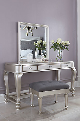 Here's to vanity in the best sense of the word. The Coralayne vanity and mirror set allures with the glitz and glam befitting silver screen queens. Exquisite frame's metallic tone channels that Hollywood Regency flair you've been dreaming of. Faux shagreen texturing on the drawer fronts and a touch of bejeweling on the sculptural pulls elevate Coralayne to interior fashion's A list.Made of veneers, wood and engineered wood | Metallic sheen finish | Faux shagreen drawer fronts | Chrome-tone pulls with faux crystal bejeweling | 3 felt-lined drawers with dovetail construction and metal ball bearing slides | Cabriole legs with stretchers | Mirror attaches to back of vanity | Assembly required | Estimated Assembly Time: 50 Minutes