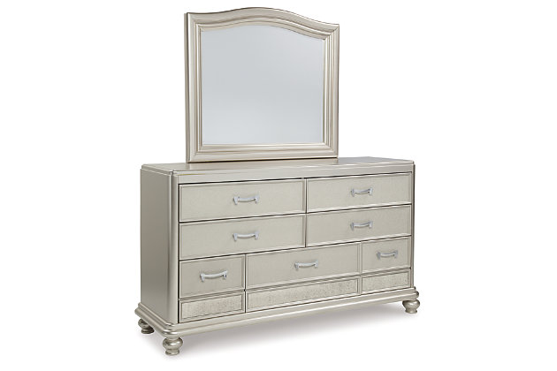The Coralayne dresser and mirror set allures with the glitz and glam befitting silver screen queens. Exquisite frame's metallic tone channels that Hollywood Regency flair you've been dreaming of. Faux shagreen texturing on the drawer fronts, a touch of bejeweling on the sculptural pulls and a strip of mirror sheen elevate Coralayne to interior fashion's A list.Made of veneers, wood and engineered wood | Metallic sheen finish | Faux shagreen drawer fronts | Mirror border detailing | Chrome-tone pulls with faux crystal bejeweling | 7 smooth-gliding drawers with dovetail construction and metal ball bearing slides | 3 top drawers felt lined | Mirror attaches to back of dresser | Assembly required | Includes tipover restraint device | Estimated Assembly Time: 35 Minutes