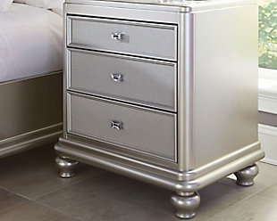 The Coralayne nightstand allures with the glitz and glam befitting silver screen queens. Exquisite frame's metallic tone channels that Hollywood Regency flair you've been dreaming of. Faux shagreen texturing on the drawer fronts and a touch of bejeweling on the sculptural pulls elevate Coralayne to interior fashion's A list.Made of veneers, wood and engineered wood | Faux shagreen drawer fronts | Chrome-tone pulls with faux crystal bejeweling | 3 smooth-gliding drawers with dovetail construction and metal ball bearing slides | Felt-lined top drawer | Assembly required | Small Space Solution | Estimated Assembly Time: 15 Minutes