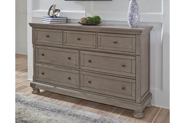 Satisfying your taste for tradition, the Lettner dresser sports serene sophistication. Forever classic design details—inlaid panels, silvertone patina hardware and bun feet—are so easy to love. A burnished light gray finish elevates the look with modern sensibility. Seven roomy drawers keep your wardrobe organized in style, and a hidden pull-out tray behind the top middle drawer puts your small valuables out of sight.Dresser only | Made of veneers, wood and engineered wood | Silvertone patina hardware | 7 smooth-gliding drawers with dovetail construction (pull-out tray and top drawers felt lined) | Includes tipover restraint device | Estimated Assembly Time: 15 Minutes