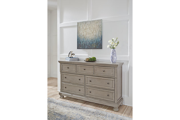 Satisfying your taste for tradition, the Lettner dresser sports serene sophistication. Forever classic design details—inlaid panels, silvertone patina hardware and bun feet—are so easy to love. A burnished light gray finish elevates the look with modern sensibility. Seven roomy drawers keep your wardrobe organized in style, and a hidden pull-out tray behind the top middle drawer puts your small valuables out of sight.Dresser only | Made of veneers, wood and engineered wood | Silvertone patina hardware | 7 smooth-gliding drawers with dovetail construction (pull-out tray and top drawers felt lined) | Includes tipover restraint device | Estimated Assembly Time: 15 Minutes
