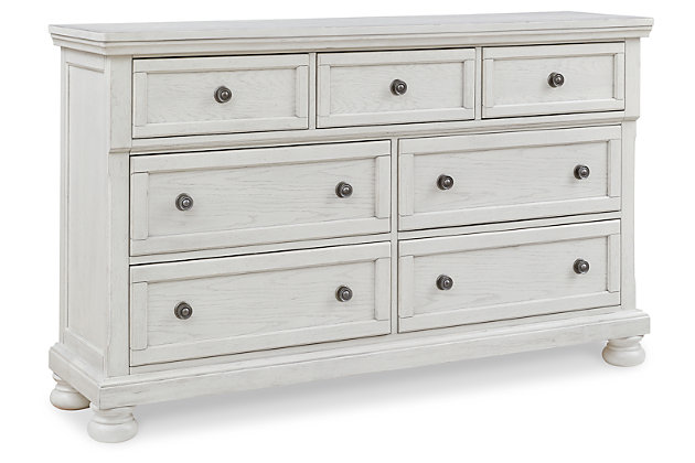 Elegant, timeless furnishings take your bedroom to the next level. Nothing does that better than the Robbinsdale dresser. The antiqued white finish with a wonderful grain texture oozes sophistication, while the dark bronze-tone hardware adds an ornate touch. A hidden pull-out tray behind the top middle drawer puts your small valuables out of sight. Felt-finished top drawers round out the piece for the ultimate tasteful bedroom. Dresser only | Made with select oak veneer, engineered wood and solid wood components | Antiqued white finish with grain texture | Dark bronze-tone knobs | 7 smooth-gliding drawers with dovetail construction and metal ball bearing side glides (pull-out tray and top drawers felt lined) | Assembly required | Estimated Assembly Time: 15 Minutes