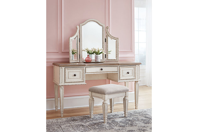 Elevating the art of traditional cottage styling, the Realyn 3-piece vanity set is your dream bedroom retreat realized. Antiqued two-tone aesthetic blends a chipped white with a distressed wood finished top for added charm. Framed drawer fronts and a plushly upholstered stool add refinement, while the tri-panel mirror lends a classic touch.Includes vanity, three-panel mirror and upholstered stool | Made of veneers, wood and engineered wood, with cast resin components | Stool with polyester upholstery | Antiqued two-tone finish | 3 smooth-gliding drawers with dovetail construction | Dark bronze-tone finished metal hardware | Estimated Assembly Time: 30 Minutes
