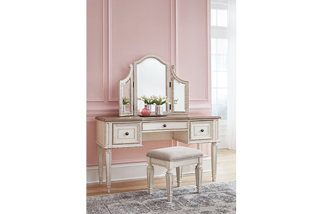 Elevating the art of traditional cottage styling, the Realyn 3-piece vanity set is your dream bedroom retreat realized. Antiqued two-tone aesthetic blends a chipped white with a distressed wood finished top for added charm. Framed drawer fronts and a plushly upholstered stool add refinement, while the tri-panel mirror lends a classic touch.Includes vanity, three-panel mirror and upholstered stool | Made of veneers, wood and engineered wood, with cast resin components | Stool with polyester upholstery | Antiqued two-tone finish | 3 smooth-gliding drawers with dovetail construction | Dark bronze-tone finished metal hardware | Estimated Assembly Time: 30 Minutes