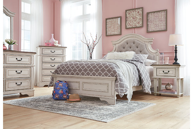 Elevating the art of traditional cottage styling, the Realyn full upholstered bed is her dream bedroom retreat realized. A curvaceous beauty, this brilliant upholstered bed wows with dramatic scalloped details and fanciful trim work and charms with a distressed chipped white finish for heirloom appeal. Deep tufting on the cushioned upholstered headboard adds such a cozy element sure to please. Mattress and foundation/box spring available, sold separately.Made of veneers, wood and engineered wood, with cast resin components | Includes upholstered headboard, footboard and rails | Distressed, chipped white finish | Upholstered headboard with foam cushion, button tufting | Assembly required | Mattress and foundation/box spring available, sold separately | Estimated Assembly Time: 55 Minutes