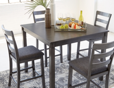 It’s so easy being gray—at least the Bridson 5-piece dining set makes it seem that way. This transitional counter-height table and barstool ensemble sports a charcoal gray finish with textured gray upholstery for an on-trend and relevant appeal. Plushly upholstered seat cushion in a practical polyfiber makes it a pleasure to linger at the table. Best of all, square table design is ideally suited for small spaces.Includes counter height table and 4 barstools | Made of wood, veneer and engineered wood | Medium charcoal gray finish | Ladderback barstools | Cushioned seats covered in textured gray polyester upholstery | Table with tapered leg design | Assembly required | Estimated Assembly Time: 90 Minutes