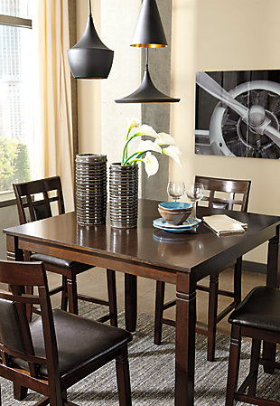 Set the scene for cool, comfortable and ultra-contemporary style with the Bennox counter table set. Counter-height design makes eating in feel more like dining out at a trendy pub. Richly upholstered in a practical faux leather with welcome back supports, the four bar stools are sure to satisfy.Includes counter height table and 4 upholstered barstools | Table made of veneers, wood and engineered wood | Wood frame barstools | Cushioned backs and seats with vinyl upholstery | Assembly required | Excluded from promotional discounts and coupons | Estimated Assembly Time: 60 Minutes