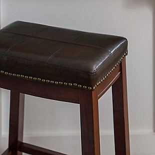Raise the bar on style with this simply striking upholstered bar stool in dark brown with brown upholstery. Thickly padded seat covered in easy-clean vinyl caters to your comfort level.Made of wood | Dark brown finish | Faux leather upholstery with foam padding | Contoured saddle seat | Nailhead trim | Footrest | Protective glides under legs | Assembly required