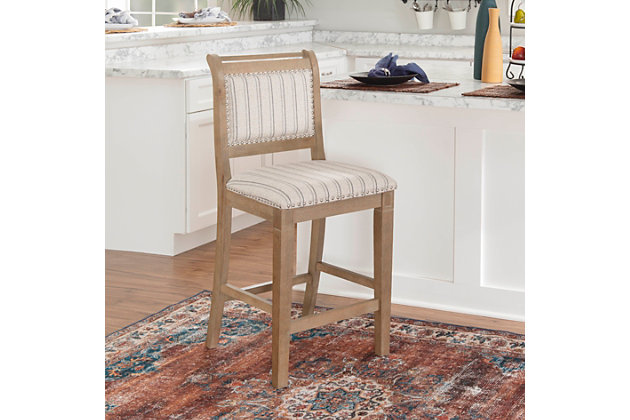 French style and farmhouse design combine to create the Hedi bar stool. The washed finished wood is perfectly accented by the stripe ticking fabric and brushed silvertone nailheads. Footrails provide stability and durability. Counter height.Made of wood | Foam cushioned seat | Brushed silvertone nailhead trim | Rustic wash finish | Stripe upholstery | Counter height | Back height: 20", back width: 18" | Assembly required