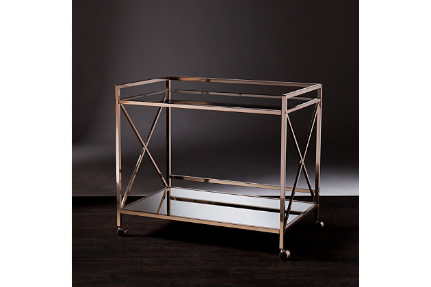 Conjure a scene a la Gatsby with this elegant bar cart. Sleek, linear architecture contrasts with the luxurious metallic goldtone finish, high-shine mirrored shelf and glossy glass tabletop. X-frame sides give a nod to the lavish lifestyles of the '20s, while two open shelves provide plenty of space for your martinis, stemware and garnishes. Designed to keep the party on a roll, this cart includes two safety casters that lock into place.Plated iron frame in metallic goldtone finish | 5-mm tempered glass top | 5-mm mirrored glass shelf | Locking casters for easy mobility/stability | Assembly required | Assembly time frame is 15 to 30 min.