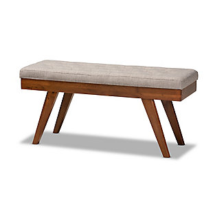 Add some visual interest to your dining room setup with the Alona dining bench. This wood bench is upholstered in a soft, gray polyester fabric that is complementary to the walnut brown finish on the wood. Influenced by elements of mid-century modern design, it features angled, tapered legs. This versatile piece works well as seating at a dining table, or is equally suitable for use as an accent piece in the entryway. The Alona dining bench is made in Malaysia and requires assembly.Mid-century modern dining bench | Foam-padded seat | Walnut brown finish | Polyester fabric upholstery | Made of rubberwood | Assembly required