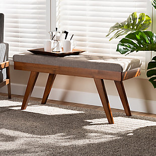 Add some visual interest to your dining room setup with the Alona dining bench. This wood bench is upholstered in a soft, gray polyester fabric that is complementary to the walnut brown finish on the wood. Influenced by elements of mid-century modern design, it features angled, tapered legs. This versatile piece works well as seating at a dining table, or is equally suitable for use as an accent piece in the entryway. The Alona dining bench is made in Malaysia and requires assembly.Mid-century modern dining bench | Foam-padded seat | Walnut brown finish | Polyester fabric upholstery | Made of rubberwood | Assembly required