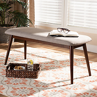 Featuring a stunning walnut brown finish, the Flora dining bench brings warmth to any dining space. Constructed from solid rubberwood, it's upholstered in a soft, durable polyester fabric and padded with foam. Expert craftsmanship is displayed in the curved edges and the smooth grained finish. Designed for everyday use, the seat is supported by four angled, tapered legs that create a modern profile while also providing ample legroom. The Flora dining bench is made in Malaysia and requires assembly.Mid-century modern dining bench | Foam-padded seat | Walnut brown finish | Polyester fabric upholstery | Made of rubberwood | Assembly required