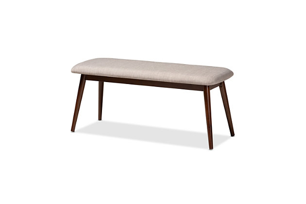 Featuring a stunning walnut brown finish, the Flora dining bench brings warmth to any dining space. Constructed from solid rubberwood, it's upholstered in a soft, durable polyester fabric and padded with foam. Expert craftsmanship is displayed in the curved edges and the smooth grained finish. Designed for everyday use, the seat is supported by four angled, tapered legs that create a modern profile while also providing ample legroom. The Flora dining bench is made in Malaysia and requires assembly.Mid-century modern dining bench | Foam-padded seat | Walnut brown finish | Polyester fabric upholstery | Made of rubberwood | Assembly required