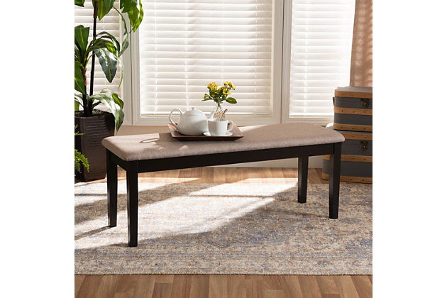 Add casual elegance to your dining room set up with the Teresa dining bench, This bench is constructed from sturdy wood, with its sleek dark brown finish complementing the soft, sand fabric upholstery. An optimal balance of comfort and style, this bench features a plush foam-padded seat, as well as long, straight legs that enable ample leg room. The Teresa dining bench is well suited for both casual and formal dining.Made of oak wood and rubberwood | Dark brown finish | Upholstered in polyester fabric and padded with foam | Straight legs | Assembly required