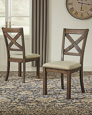 Moriville upholstered dining chair elevates the art of casual rustic style. With a distressed nutmeg finish, antiqued nailhead trim and textured polyester fabric, this upholstered dining chair with classic X back styling entices with warmth and earthy elegance. Cushioned seat accommodates lingering meals enjoyed in comfort.Made of wood | Polyester upholstery over foam cushioned seat | Nailhead trim with antiqued bronze-tone finish | Assembly required | Estimated Assembly Time: 30 Minutes