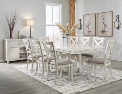 Creamy white dining room with a large rectangular dining table and eight chairs; a sideboard and decor in background