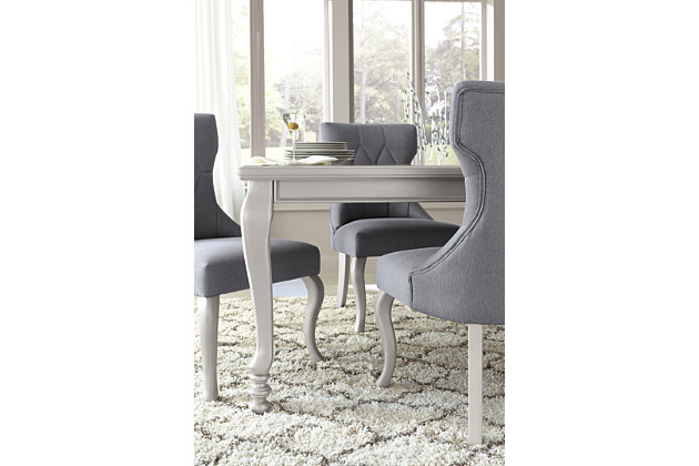 The Coralayne dining room extension table relishes the glitz and glam befitting silver screen queens. Curvaceous cabriole legs are truly alluring, as is the exquisite frame's lightly metallic finish. Faux shagreen showing through clear glass inlays melds a cool textural look with a smooth tabletop surface.Made of veneers, wood and engineered wood | Subtle metallic sheen finish | Beveled clear glass inlays | Faux shagreen embossing on tabletop | Cabriole legs | Includes 1 removable leaf | Seats up to 8 with removable leaf | Assembly required | Dining chairs sold separately | Estimated Assembly Time: 15 Minutes