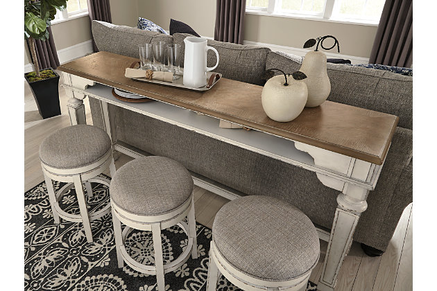 Stretch the possibilities of traditional cottage design with the Realyn long counter table. This slim, stylish table with dual open cubbies is perfectly scaled for large and small spaces alike. Place behind a sofa or sectional to enhance your entertainment area or serve up a place for casually cool dining. Its antiqued two-tone aesthetic pairs a chipped white with distressed wood finished top for twice the charm.Made of veneers, wood and engineered wood | Antiqued two-tone finish | 2 open cubbies | Stools sold separately | Assembly required | Estimated Assembly Time: 30 Minutes