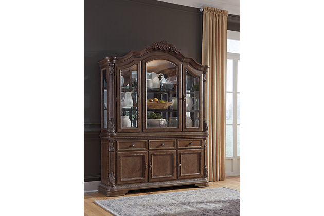 The Charmond dining room buffet’s uniquely luxurious interpretation of traditional style says it all. Exquisitely detailed with scrolled acanthus accents and treated to a multi-hued finish, it’s clearly a labor of love. Three cabinets and an expansive surface serve your entertaining needs exceptionally well.Made of veneers, wood, engineered wood and cast resin | Dark brown finish with glazed white highlights | Antiqued goldtone hardware | 3 lined drawers with black felt bottom | 1 large double cabinet and 1 smaller single cabinet, each with 1 adjustable shelf | Estimated Assembly Time: 15 Minutes