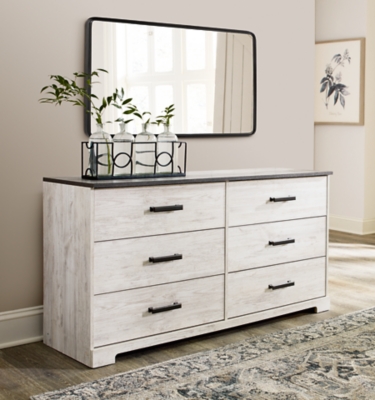 Give provincial a new meaning with the chic look of the Shawburn dresser. The two-tone finish keeps this piece light and fresh while the warm pewter-tone hardware adds an industrial touch. The distressed whitewashed body adds a delightfully homespun charm to your space.Made with engineered wood (MDF/particleboard) and decorative laminate | Whitewash replicated worn through paint | Top with rustic gray planked replicated oak grain with authentic touch | Pewter-tone pulls | 6 smooth-gliding drawers | Vinyl wrapped drawer sides and back for extra durability | Safety is a top priority, clothing storage units are designed to meet the most current standard for stability, ASTM F 2057 (ASTM International) | Drawers extend out to accommodate maximum access to drawer interior while maintaining safety | Assembly required | Estimated Assembly Time: 50 Minutes